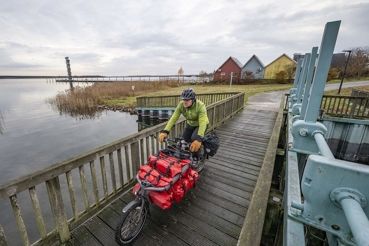 Am Wasser Gunnar Fehlau fährt auf seinem Lastenrad auf einem Bohlenweg am Wasser entlang.