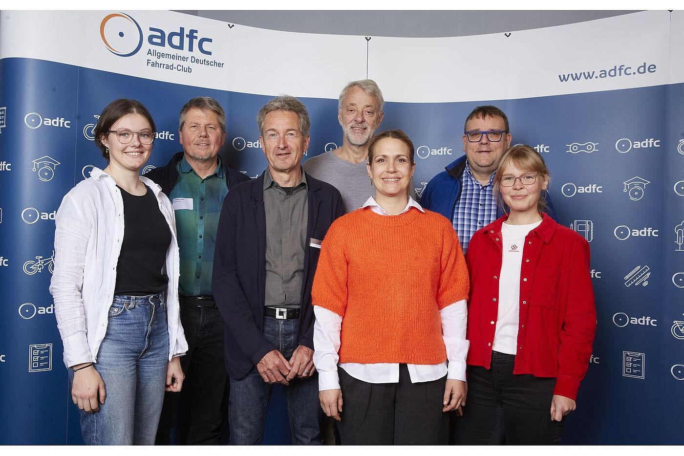 Der neue ADFC-Bundesvorstand, von links nach rechts: Lena Adam, Dr. Joachim Lohse, Christian Tänzler, Frank Masurat, Sarah Holczer, Christoph Schmidt und Vera Konrad. Sie stehen vor einer blau-weißen ADFC-Fotowand. 