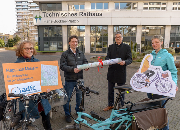 Vier Personen übergeben einen Stadtplan an Vertreter der Stadtverwaltung